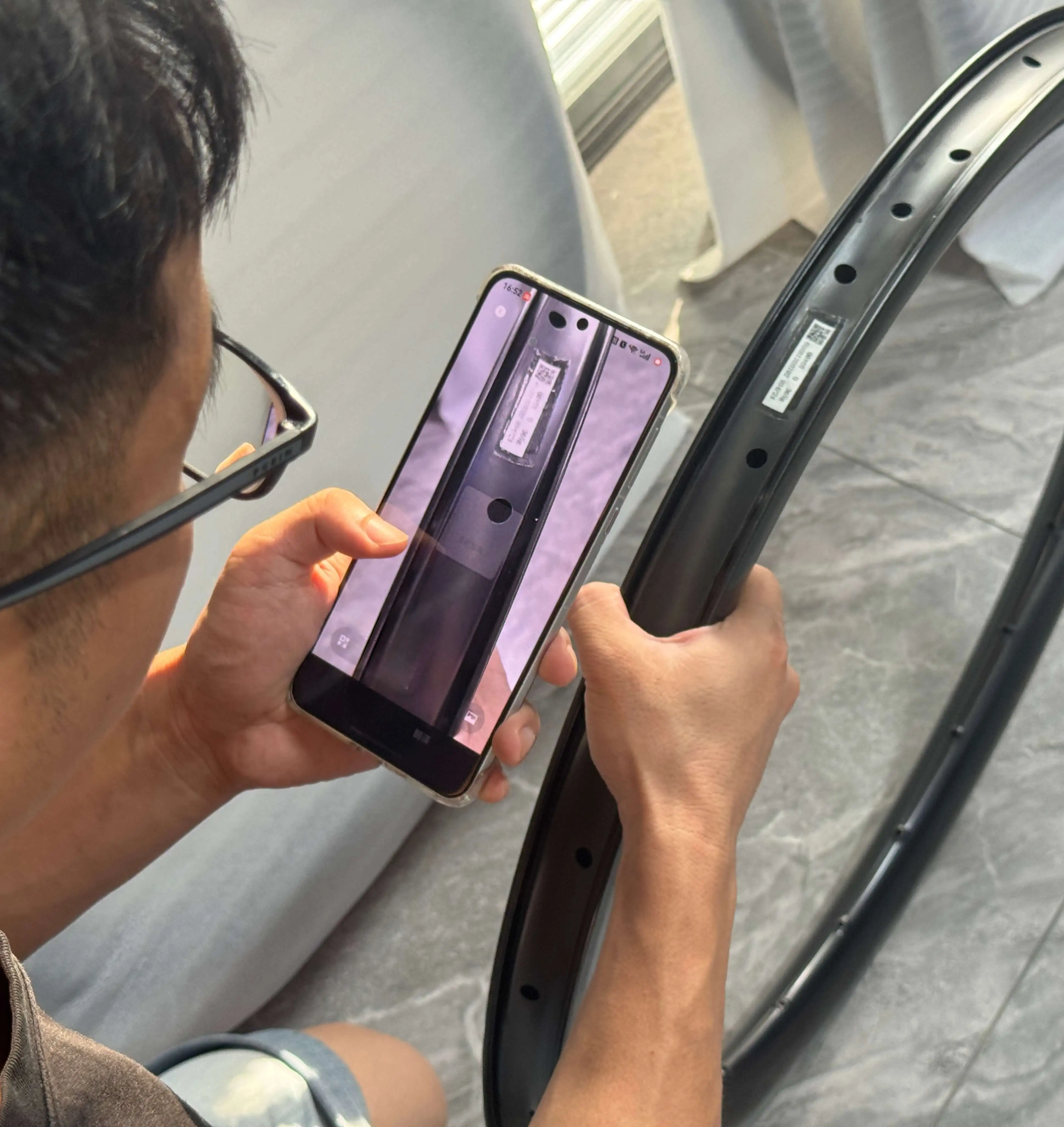 Technician scanning the QR traceability code on a carbon rim with a smartphone at Light Travel Cycling