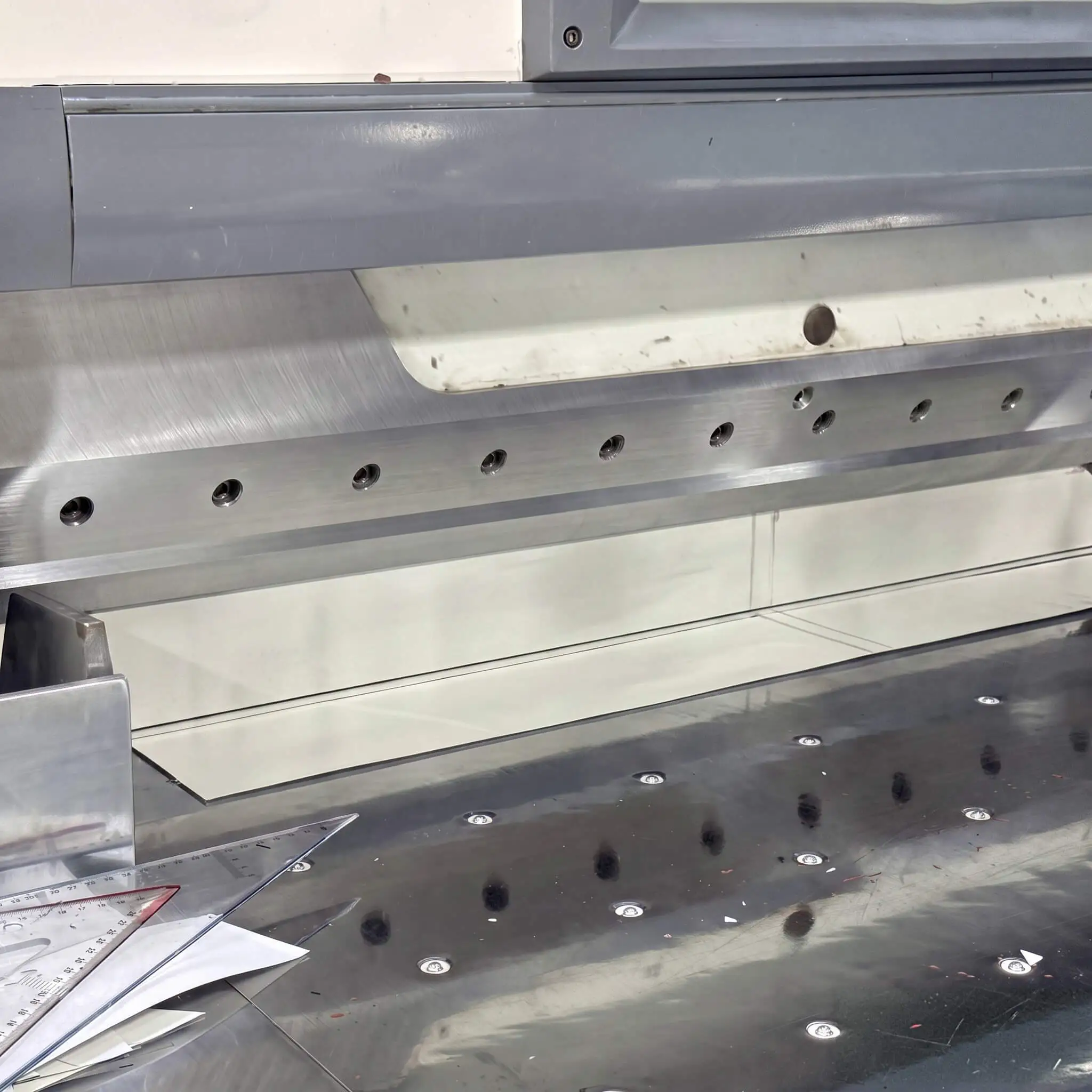 CNC cutting station at the Light Travel Cycling factory: machined rail, calibrated rulers and cutting templates used to cut carbon sheets into engineered plies