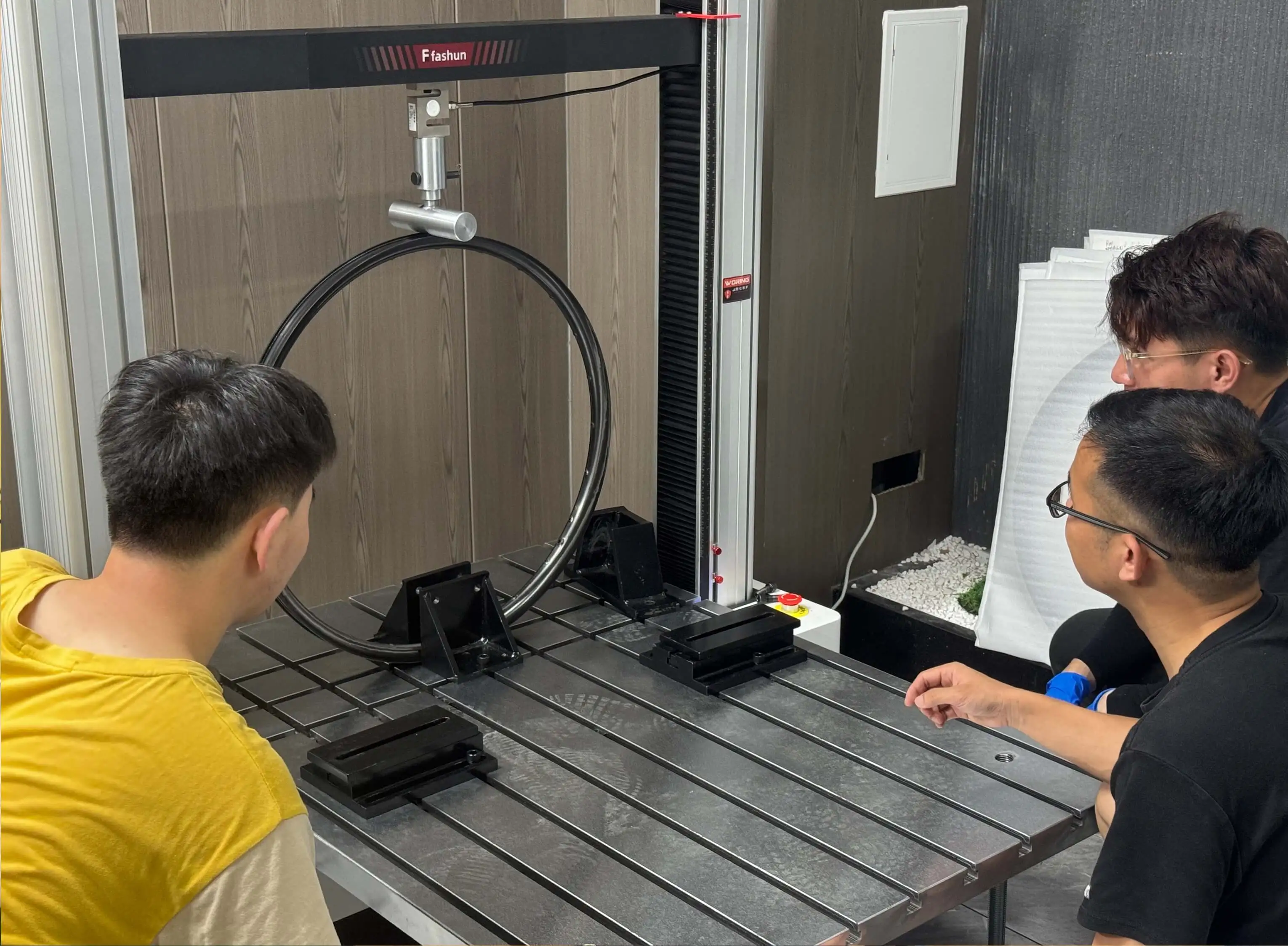 Light Travel Cycling engineers reviewing test results together beside a rim fatigue testing machine
